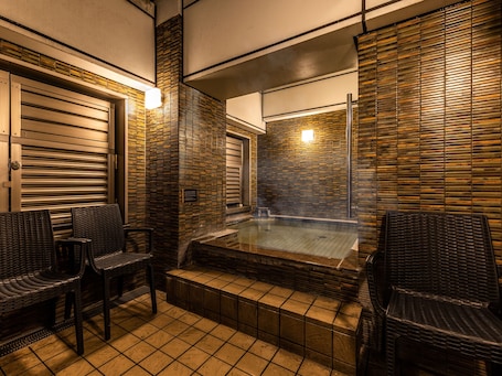 A spa area with a hot tub, wicker chairs, and tiled flooring.