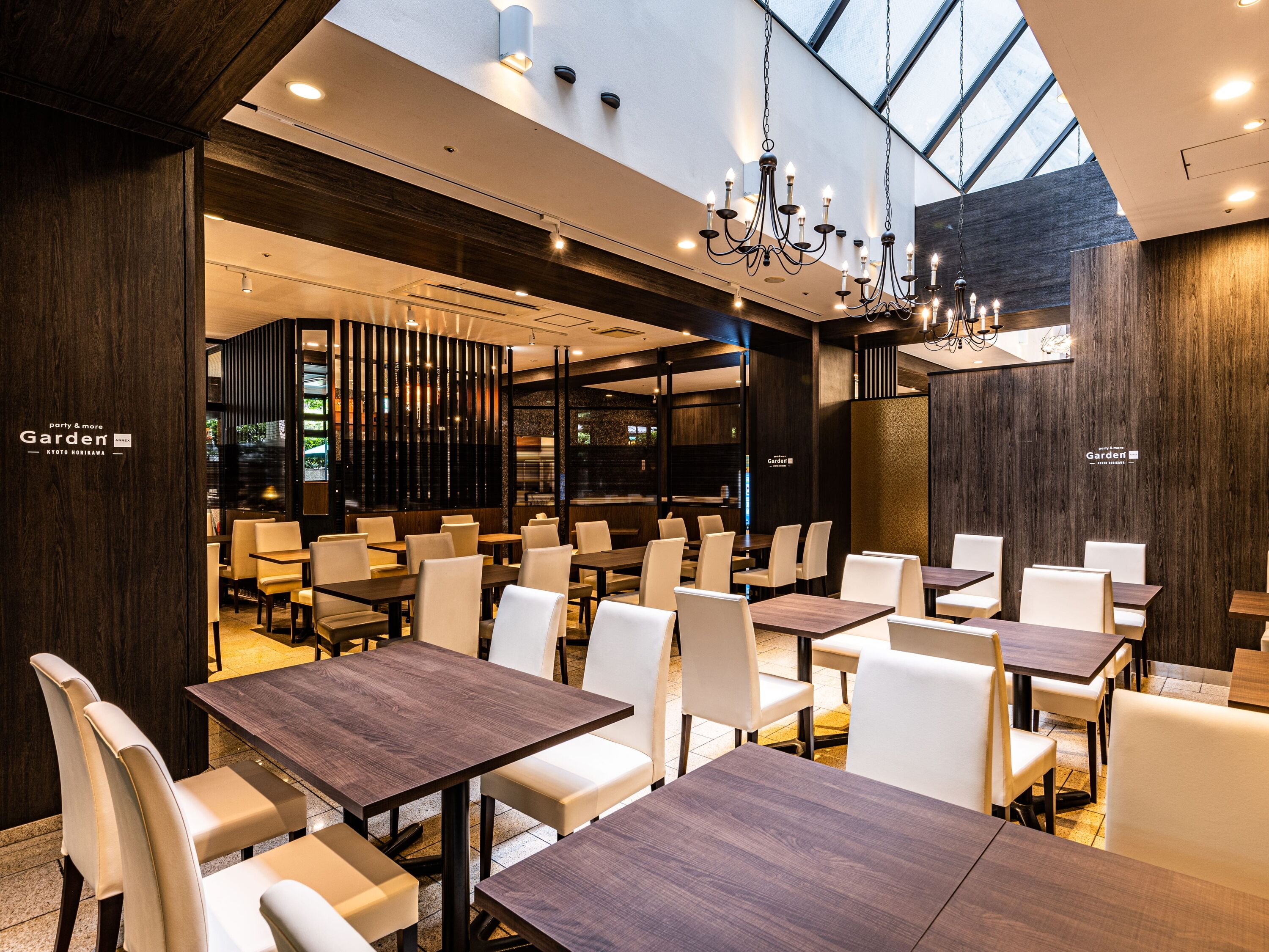 A modern restaurant with high ceilings, natural light, and a mix of wooden and metal decor.