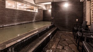 A modern outdoor pool area with a stone floor, a seating area with chairs, and a kitchen visible through a glass partition. - APA Hotel Kyoto Eki Horikawadori (Kyoto)