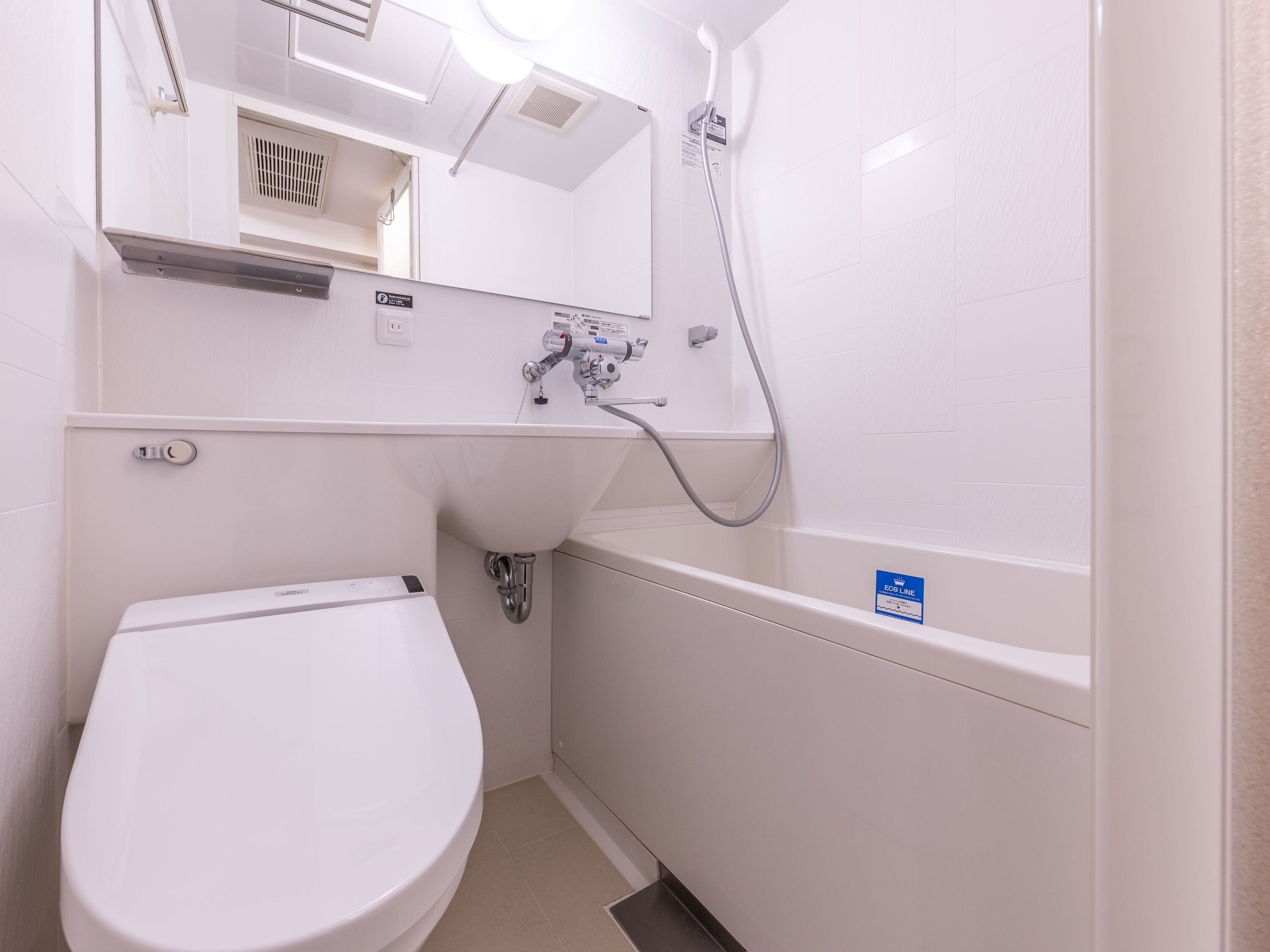 A small, white bathroom with a toilet, a sink, and a shower.