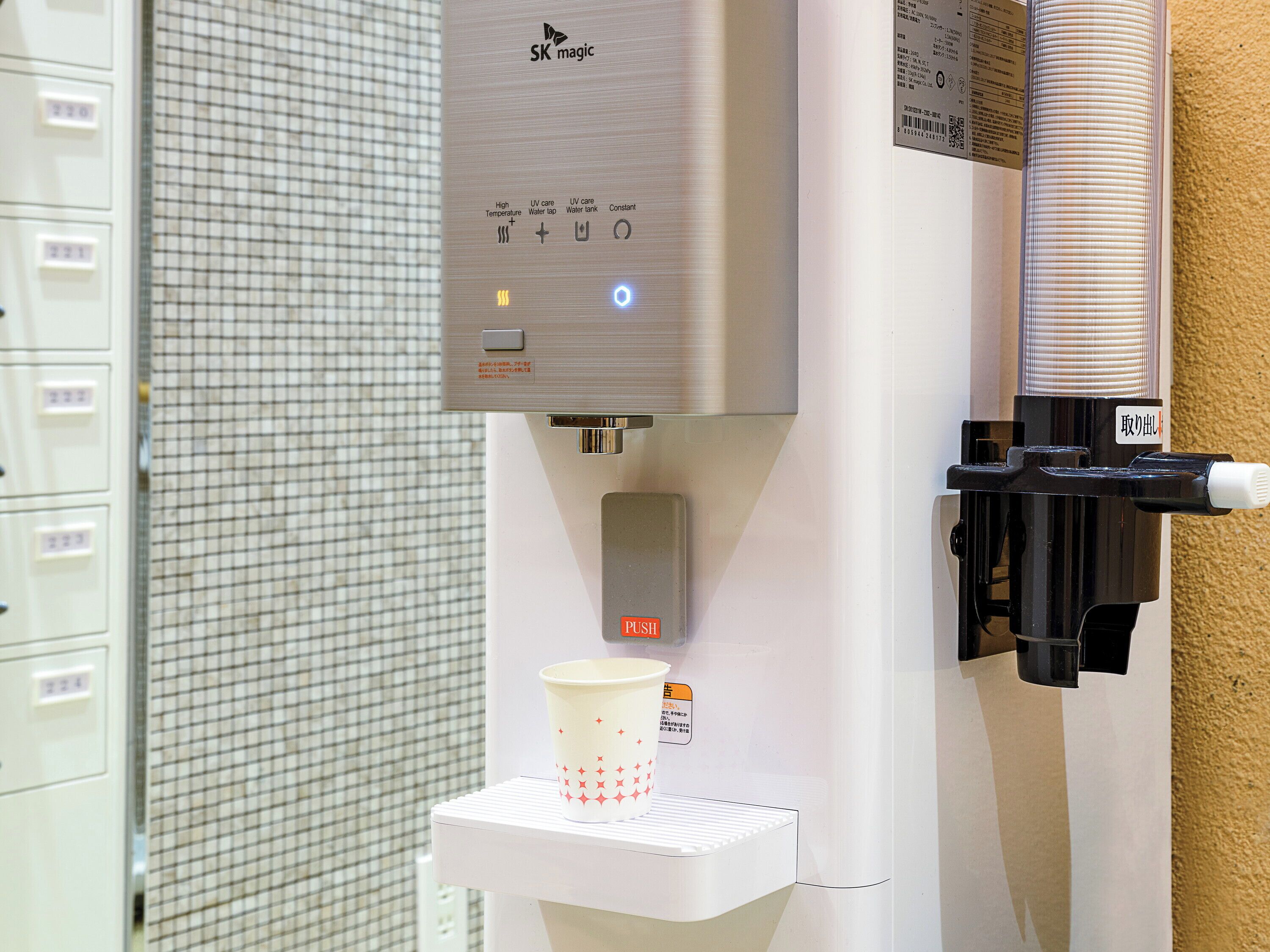 A water dispenser with a cup holder, a control panel with various settings, and a QR code.
