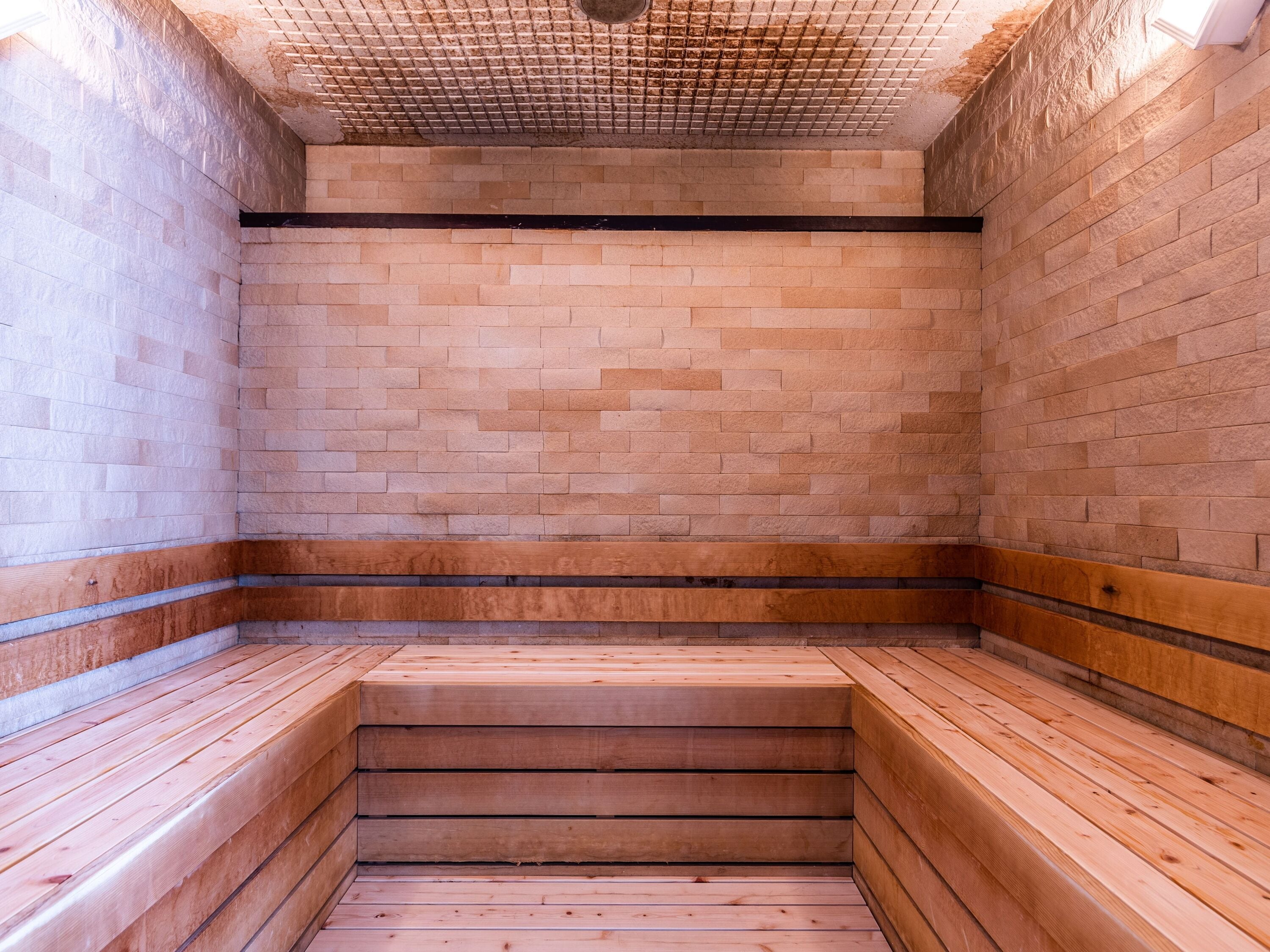 A sauna with wooden benches and a tiled ceiling.