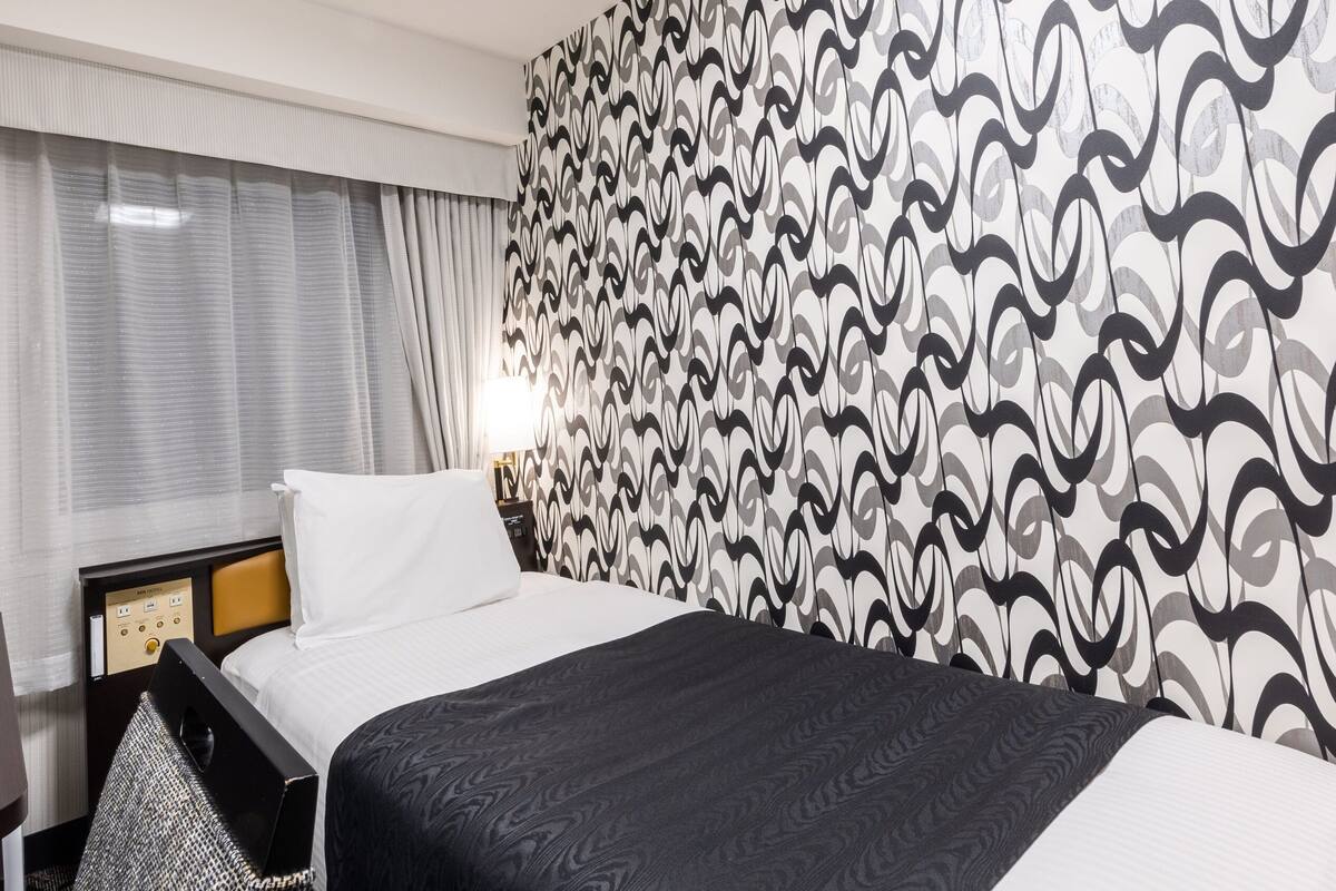 Ein Hotelzimmer mit einem Bett, einem Schreibtisch und einer Wand mit Muster.