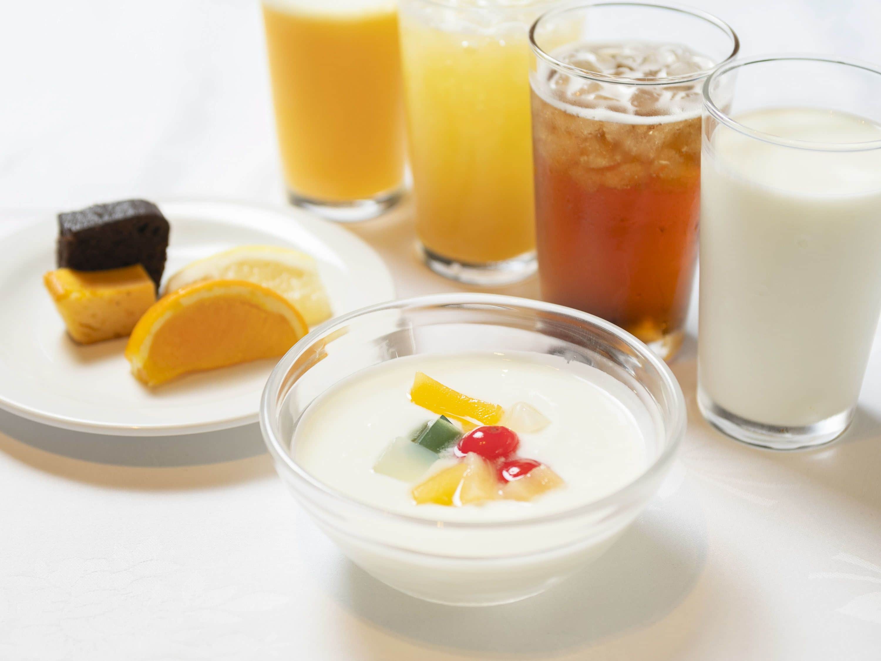 A bowl of fruit salad with a slice of lemon and a piece of cake on a plate.