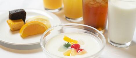 A bowl of fruit salad with a slice of lemon and a piece of cake on a plate.