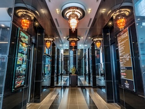 A modern hotel lobby with a central chandelier, glass walls, and a digital menu display. - APA Hotel Osaka Higobashi Ekimae Tower (Osaka)
