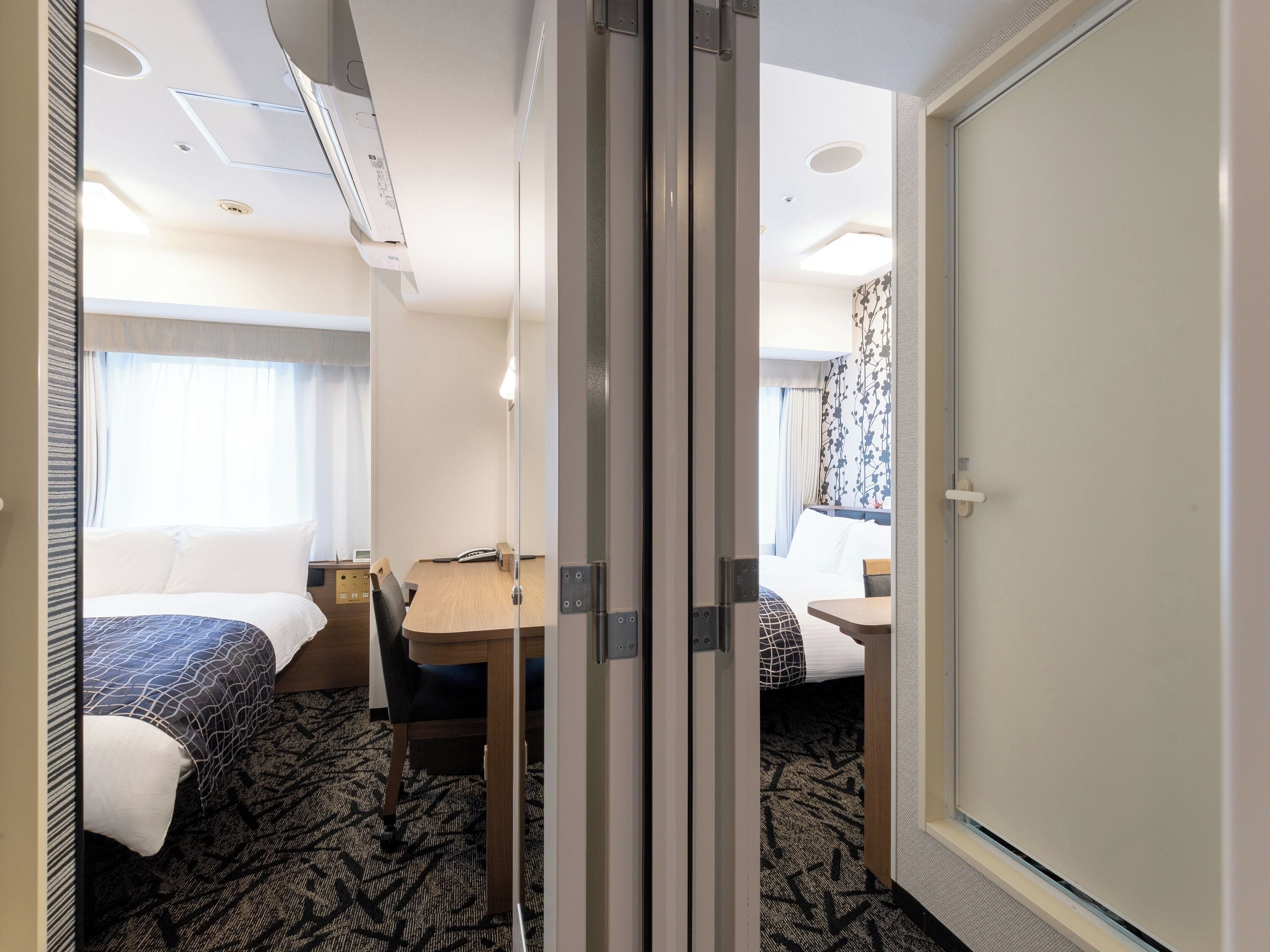 Ett hotellrum med en säng, ett skrivbord, en stol och en dörr.