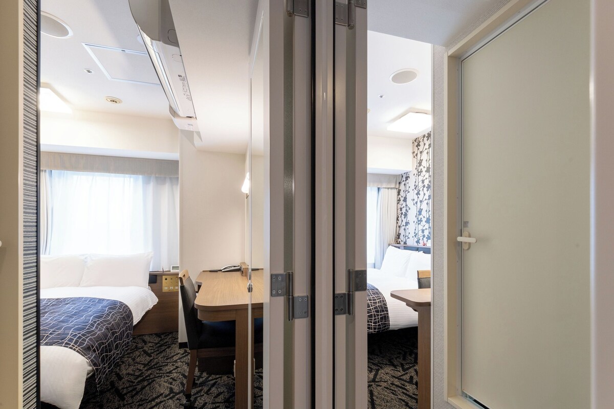 Una habitación de hotel con cama, escritorio, silla y puerta.
