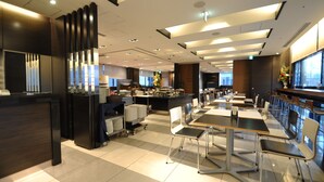 A modern hotel lobby with a reception desk, a buffet area, and a dining section with tables and chairs.