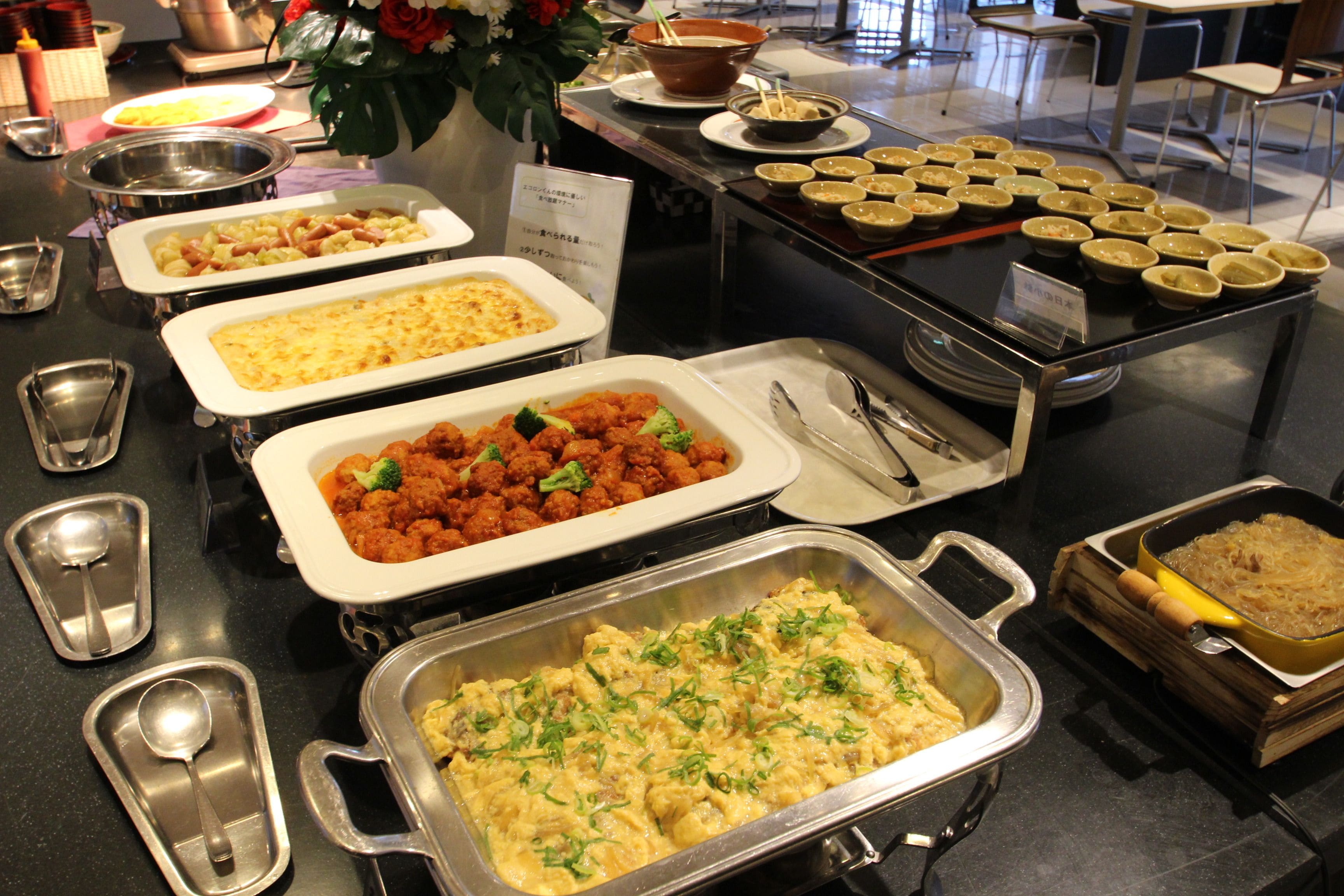A buffet with various dishes including pasta, meatballs, and casseroles.