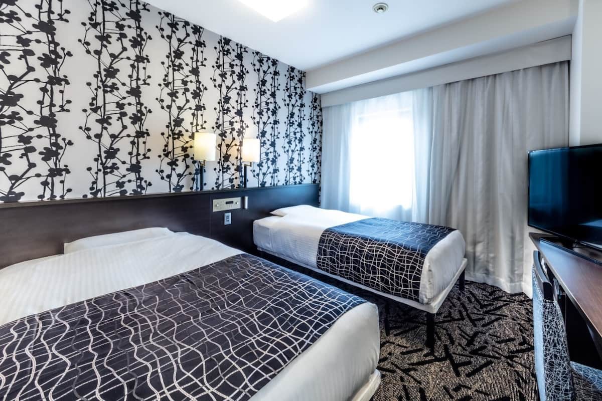 Habitación de hotel con dos camas, televisión y papel tapiz floral.