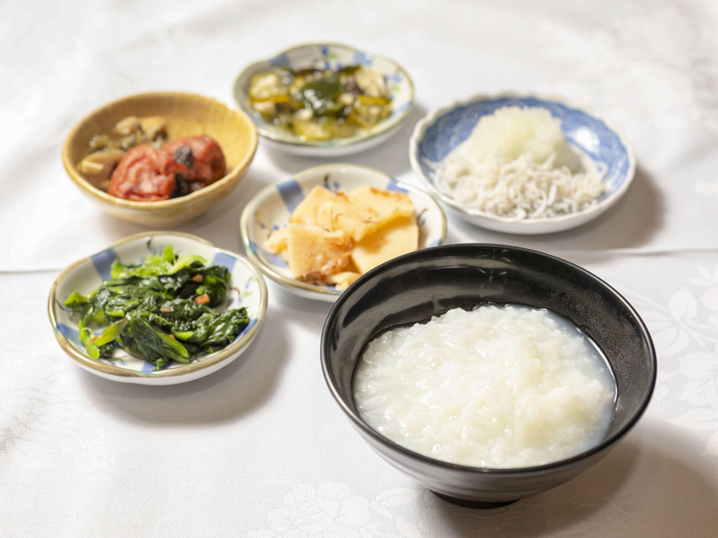 A table with various dishes including a bowl of rice, a bowl of soup, and several small dishes with different foods.