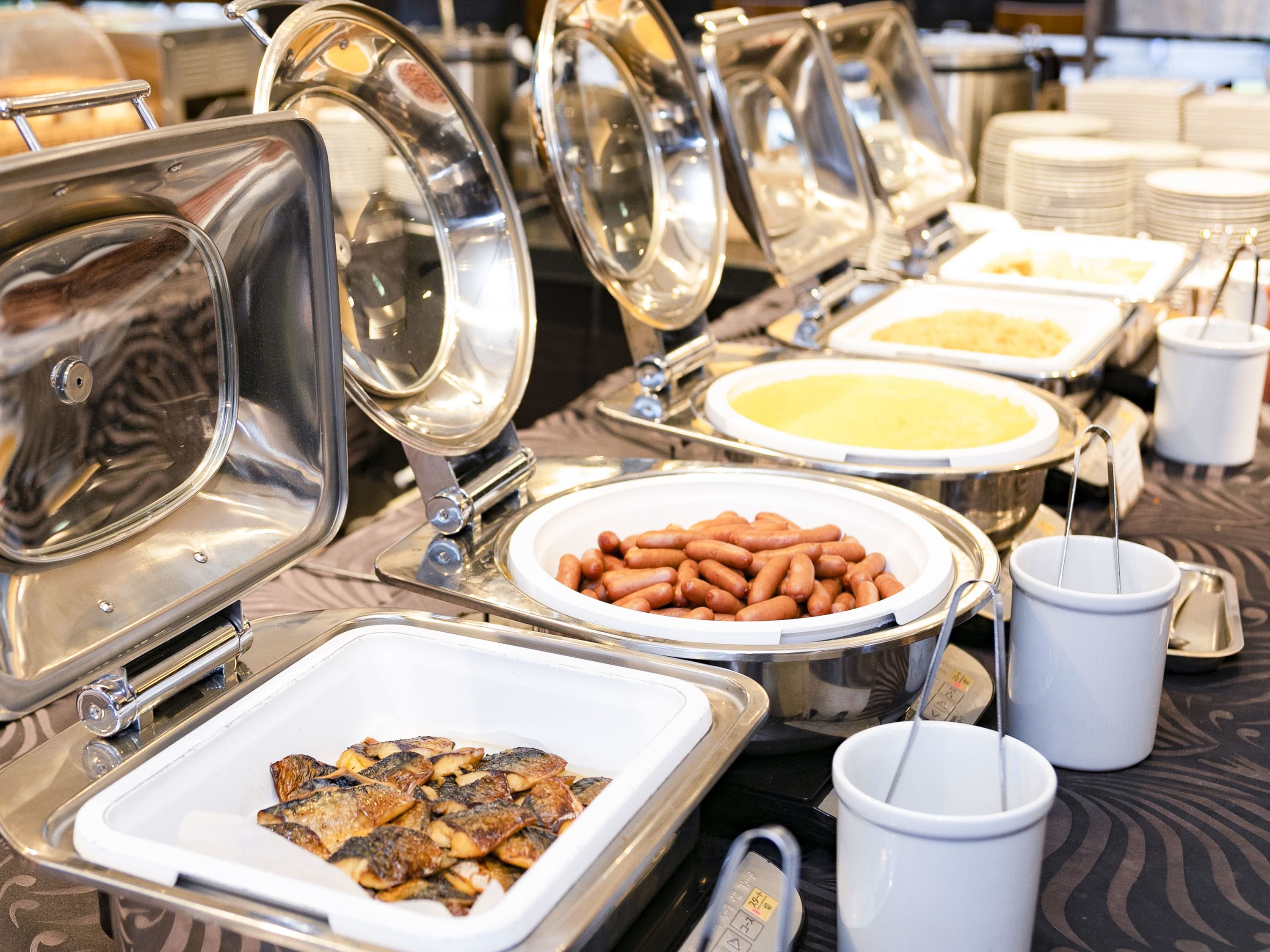 A buffet setup with various food items and serving utensils.