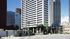 A high-rise hotel with a modern architectural design, featuring a prominent 'APA' sign at the top.