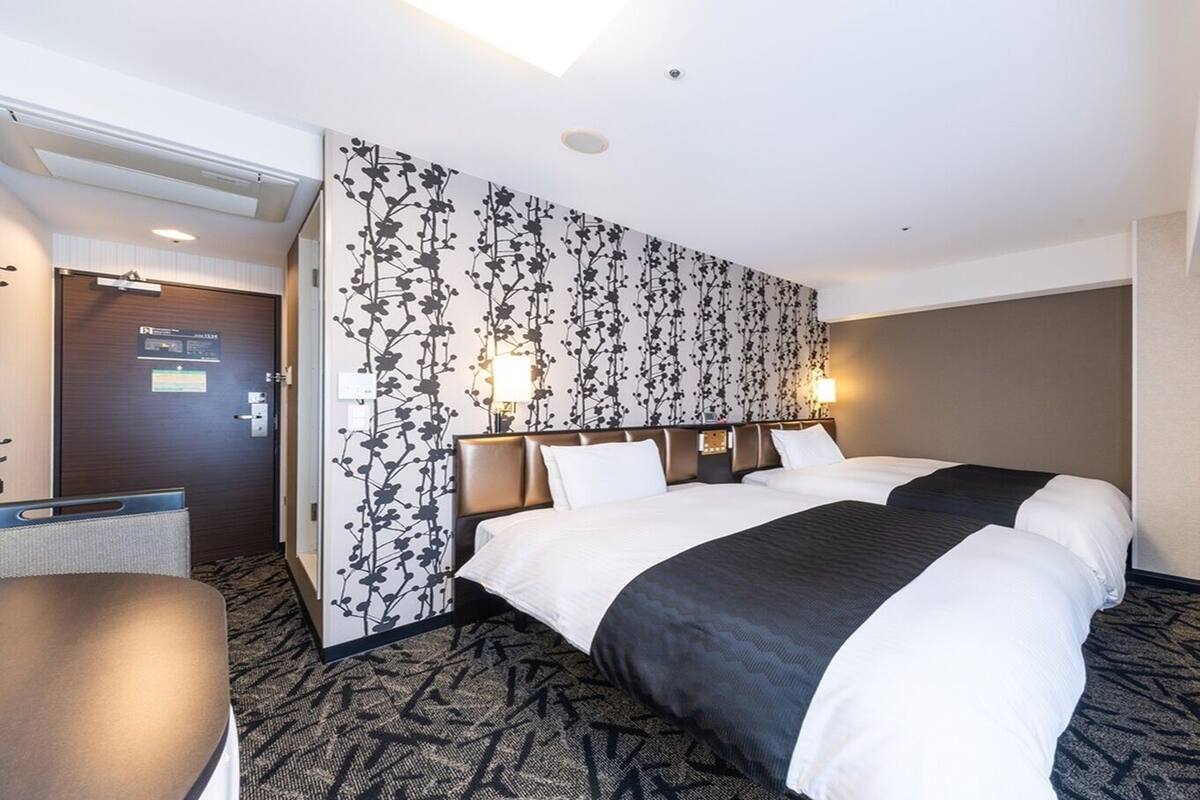 A hotel room with a bed, bedside tables, a flat-screen TV, and a patterned wall.