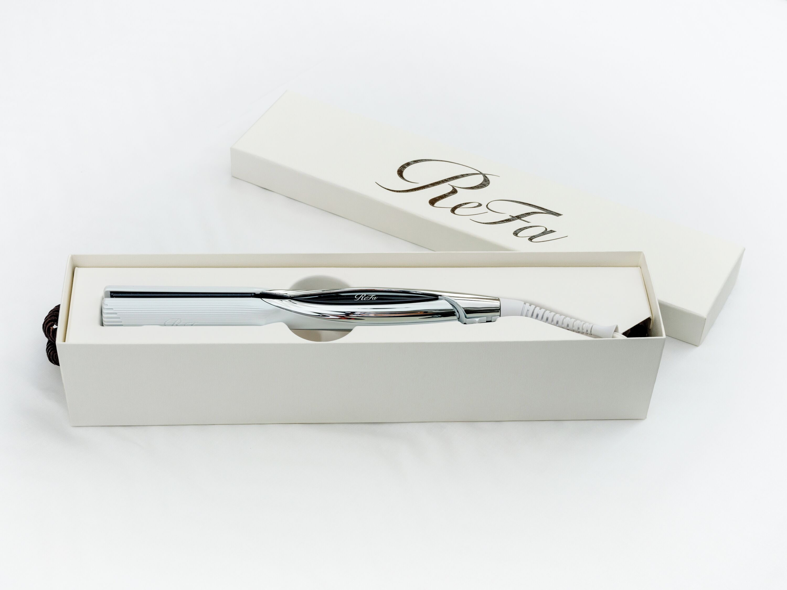 Una caja blanca con un bolígrafo y otra caja etiquetada con “ReFa” en su interior.