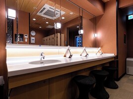 Un baño moderno con dos lavabos, un espejo grande y techo de madera.