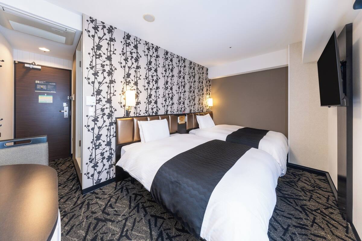 A hotel room with a large bed, a desk, and a TV.