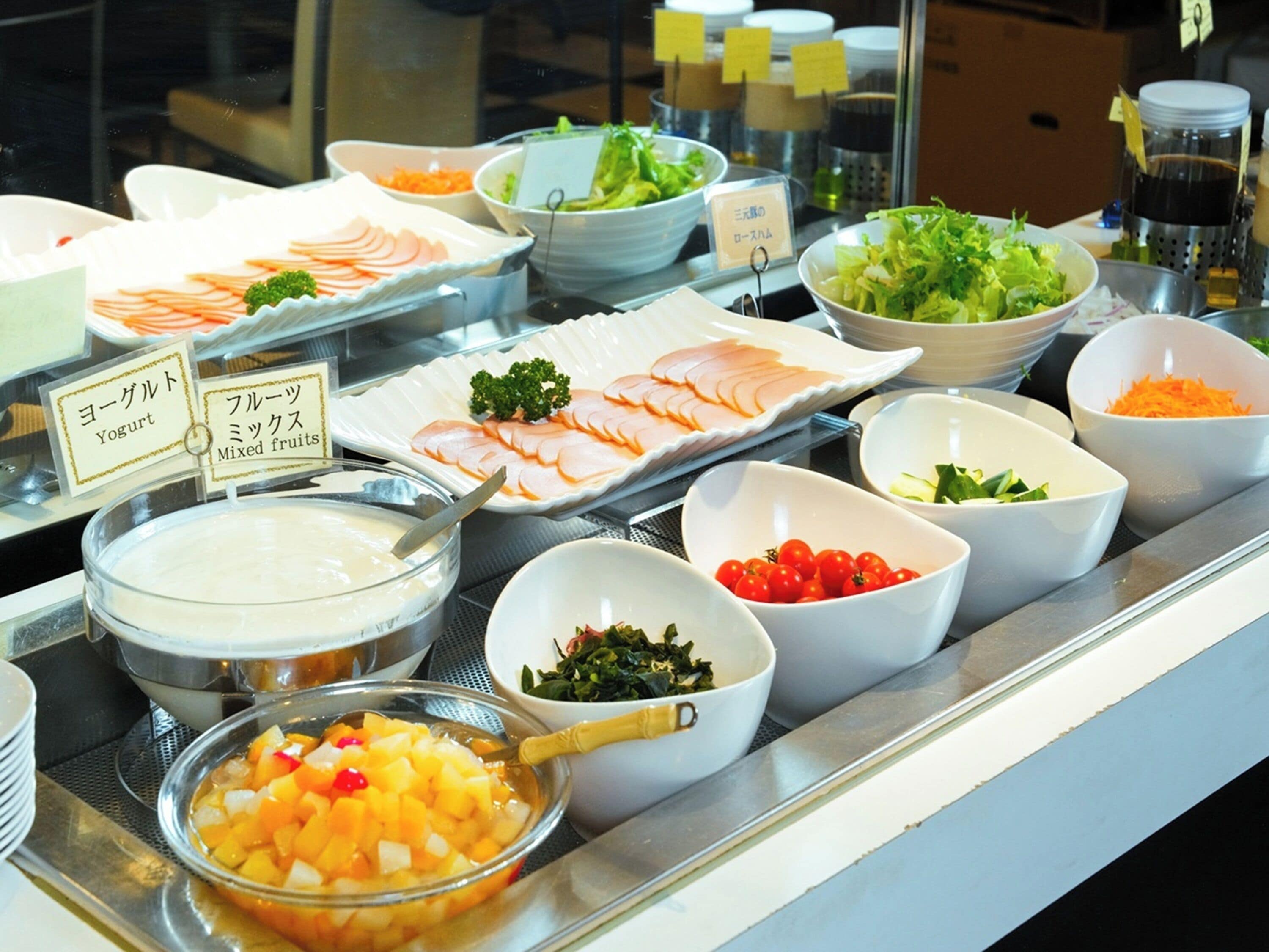 A buffet with various food items including yogurt, mixed fruits, and salads.