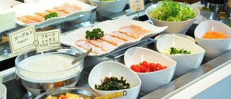 A buffet with various food items including yogurt, mixed fruits, and salads.