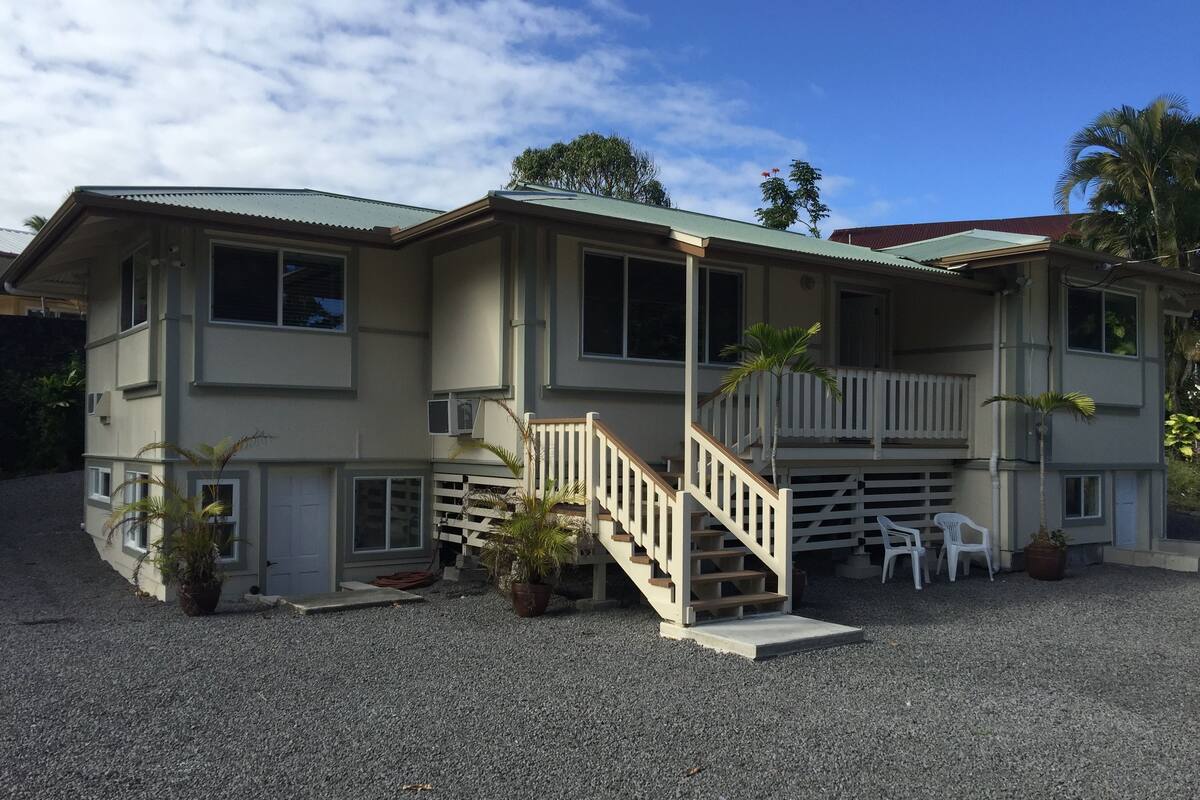 A two-story building with a balcony, a staircase, and a gravel driveway.