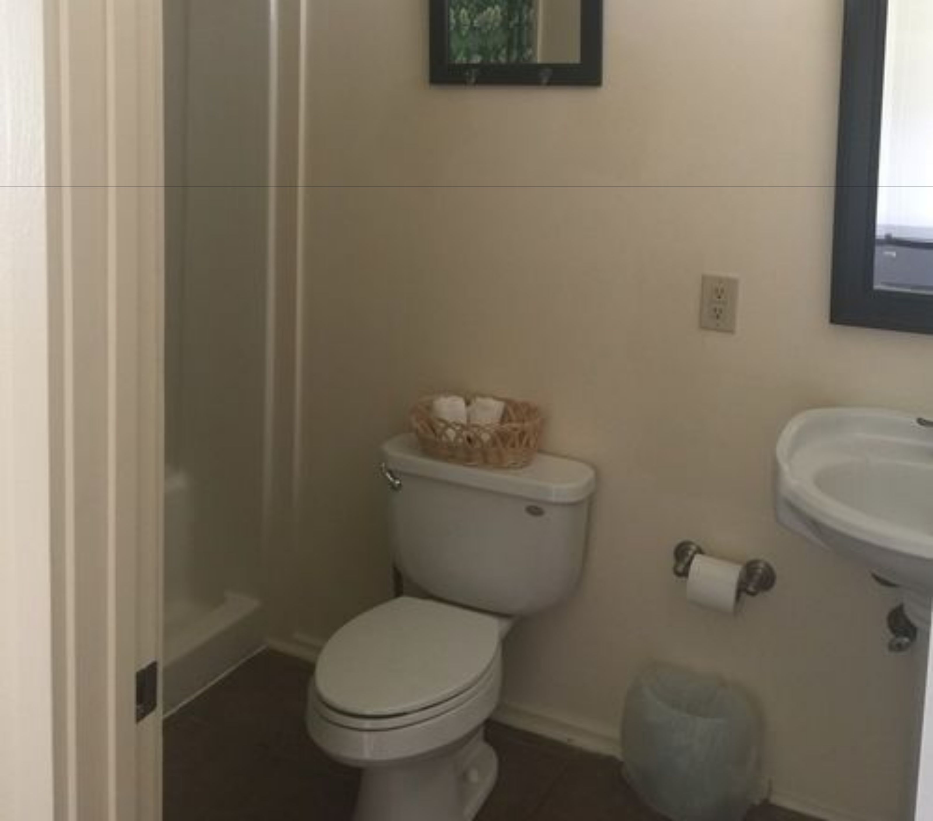 A small bathroom with a toilet, a sink, and a trash can.