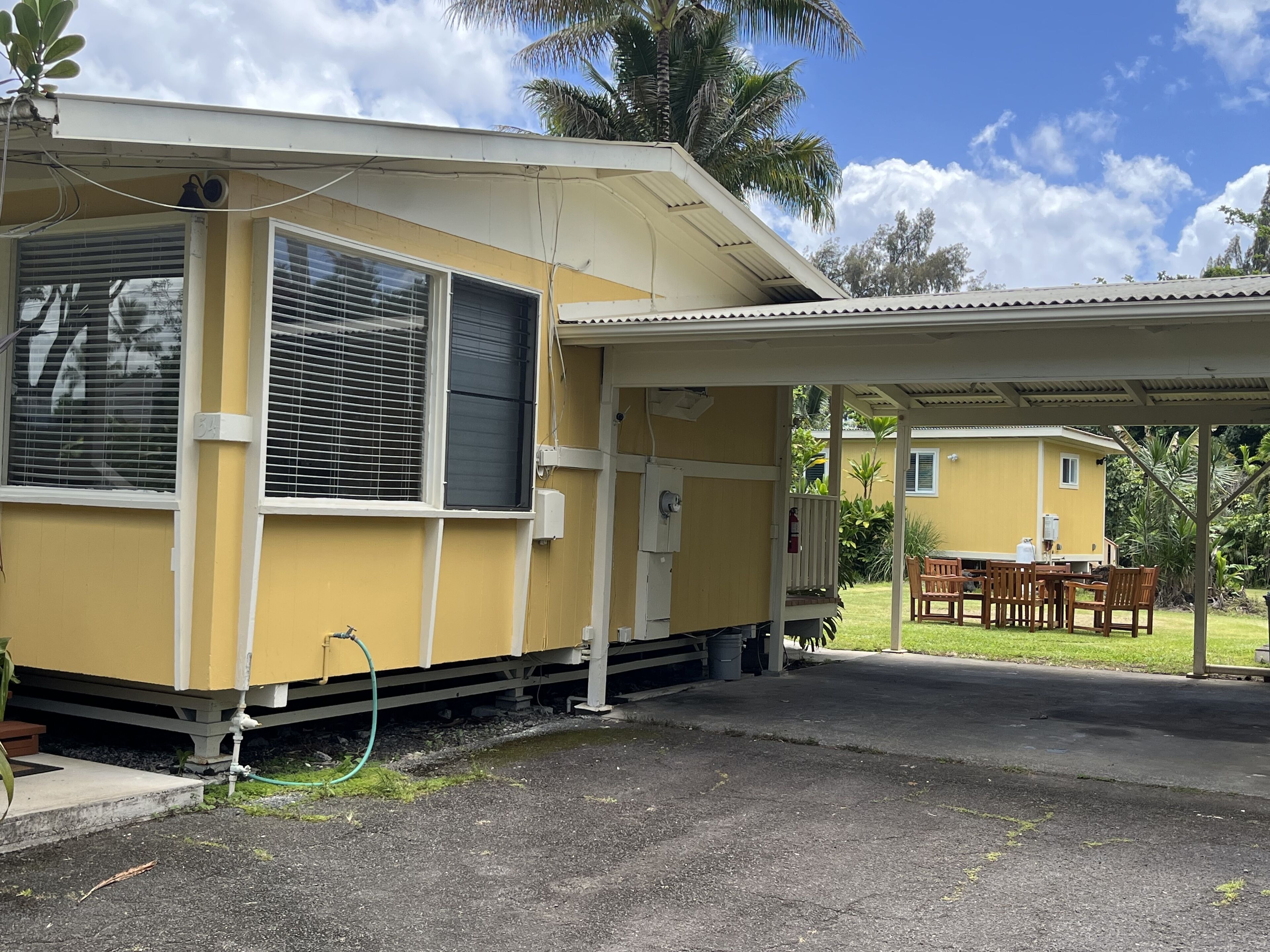 A yellow building with a covered porch and a small patio area.