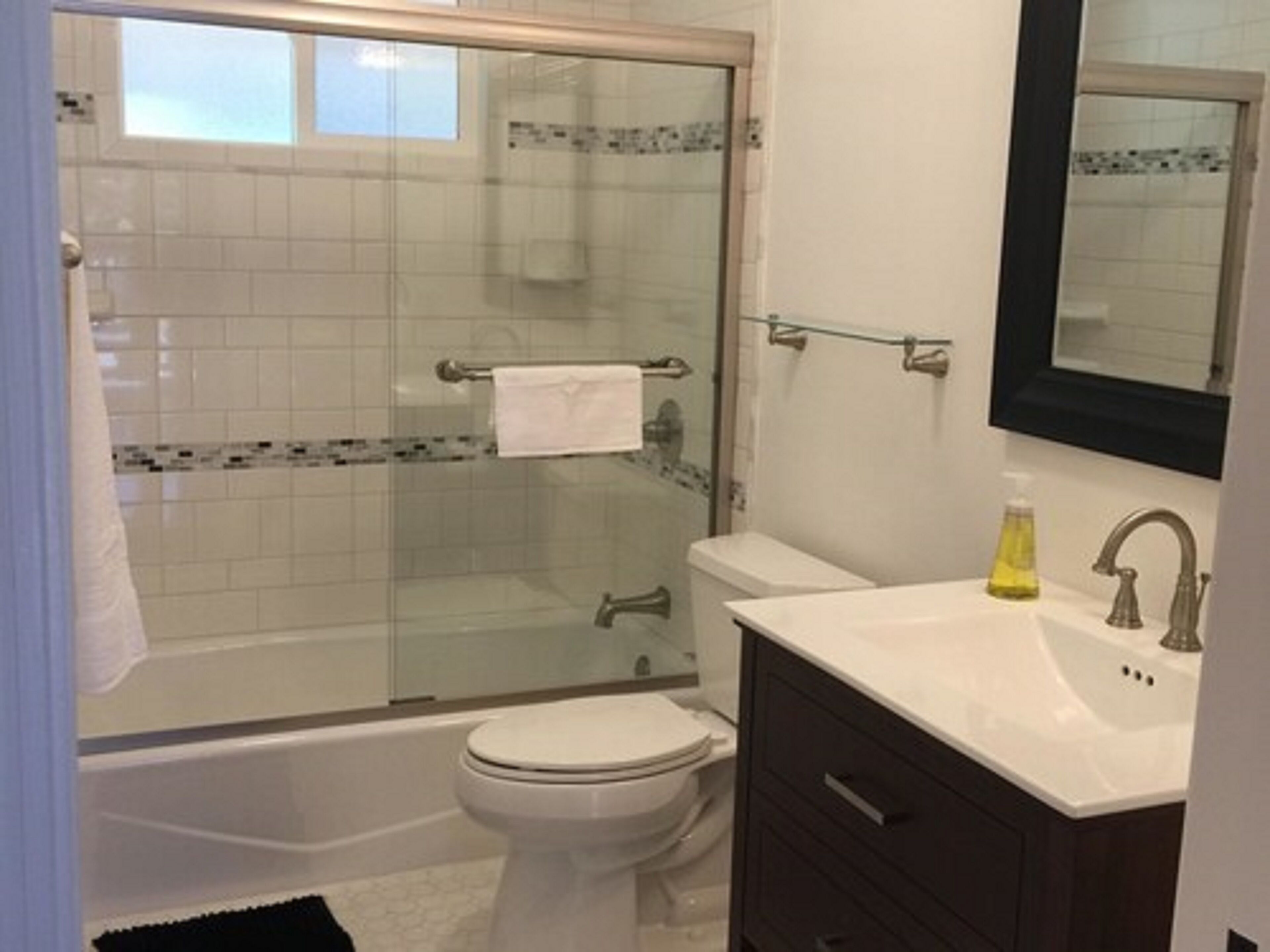 A bathroom with a glass-enclosed shower, a toilet, and a vanity with a mirror.