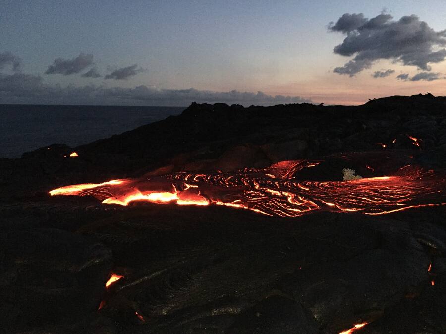 A lava flow on a dark, rocky terrain with a clear sky.