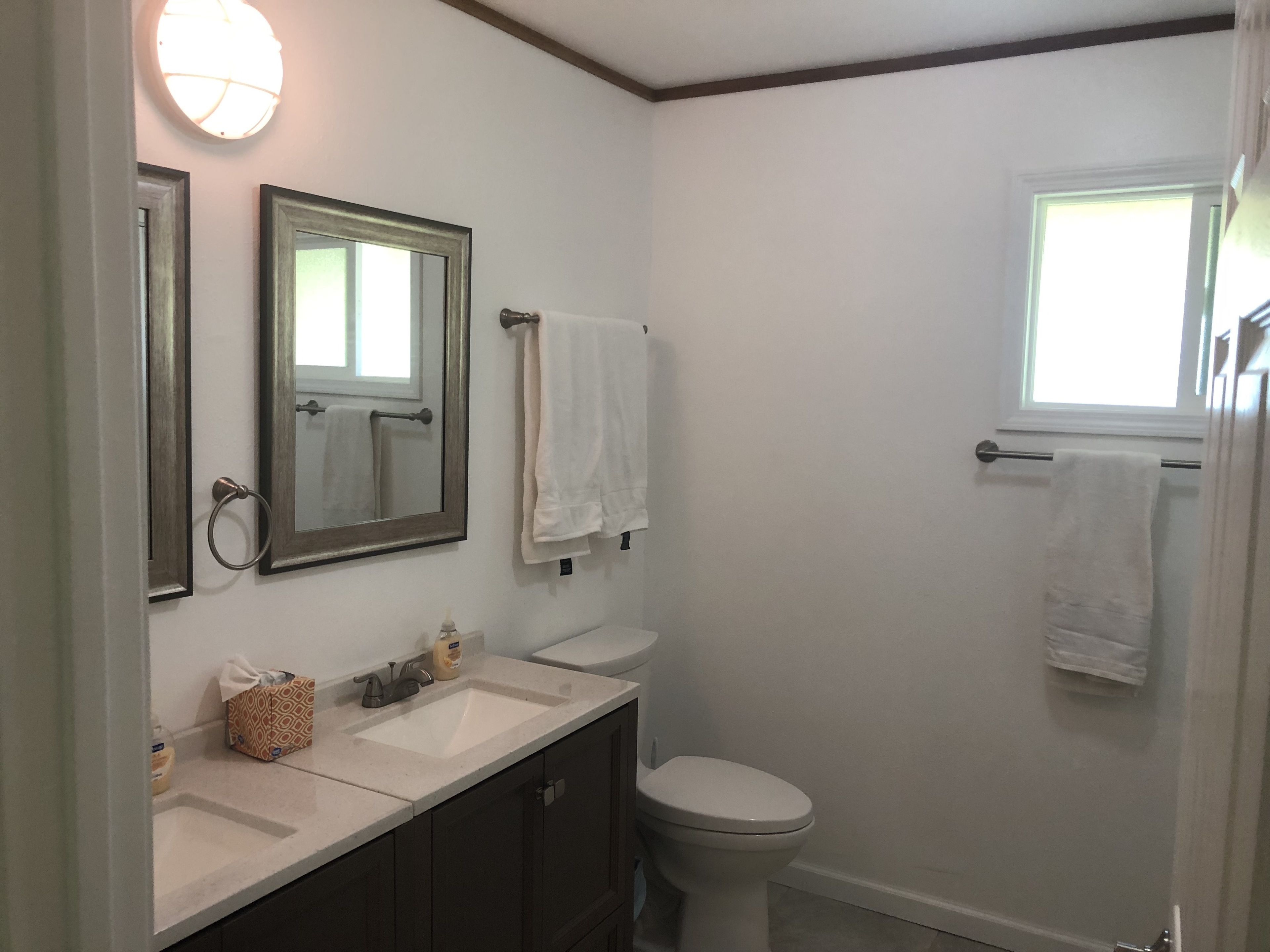 A bathroom with two sinks, a toilet, and a window.