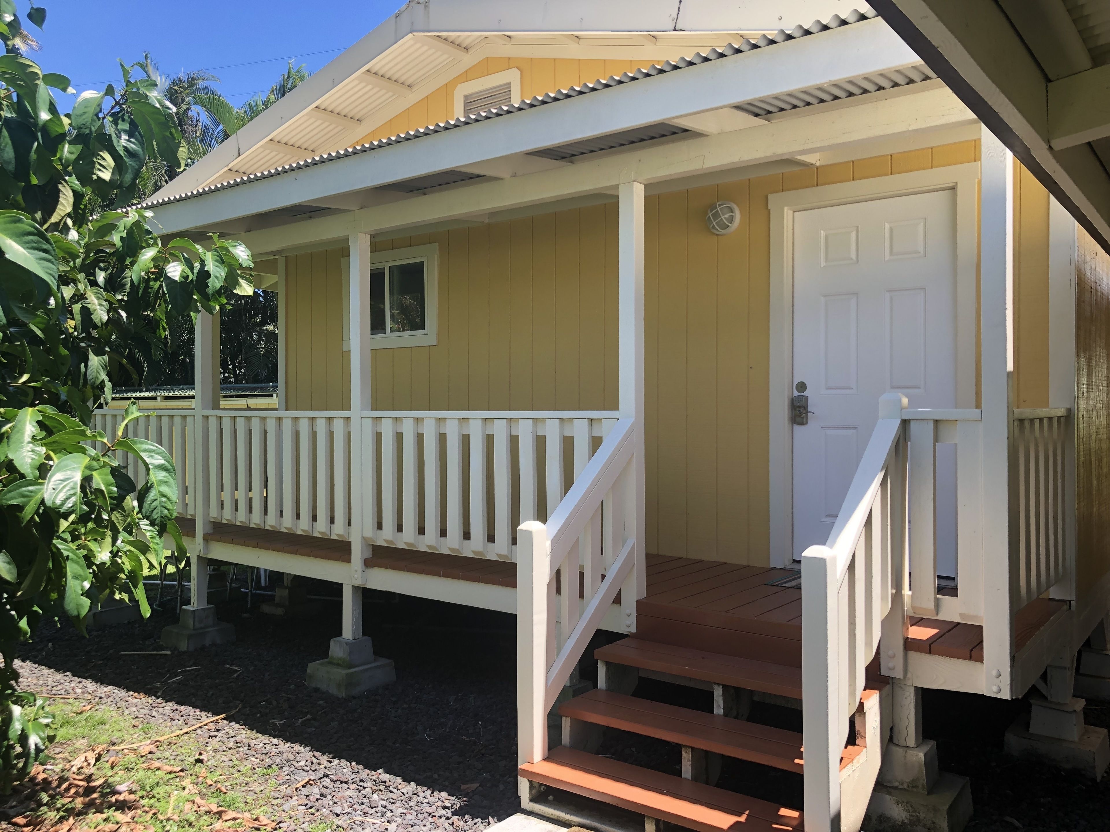 A yellow building with a white porch and a door.