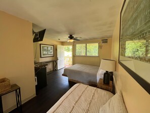 A bedroom with a bed, a desk, a chair, a ceiling fan, and a window with blinds.