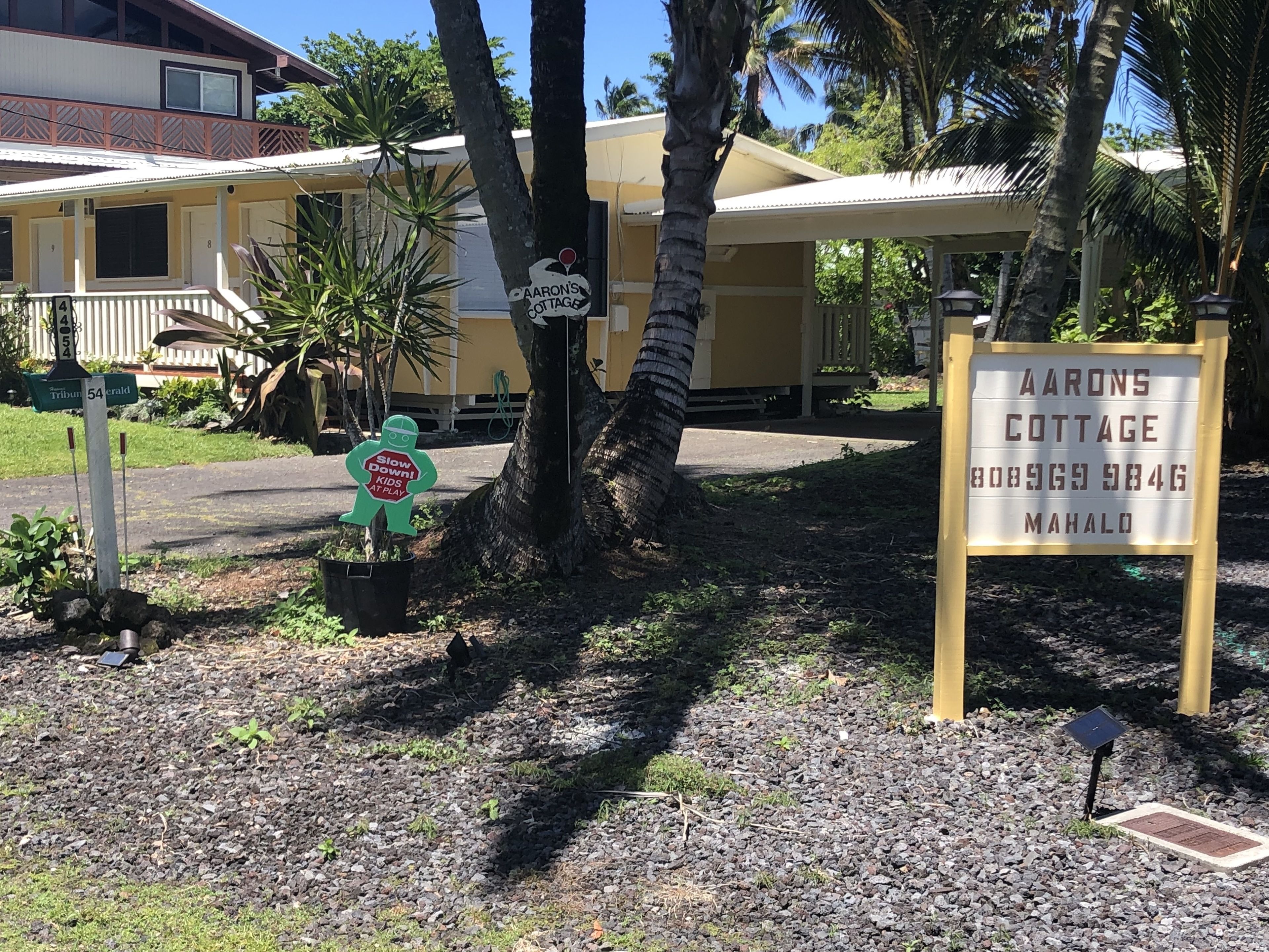 Aaron's Cottage with a signboard, a mailbox, and a 'Slow Down Kids at Play' sign.