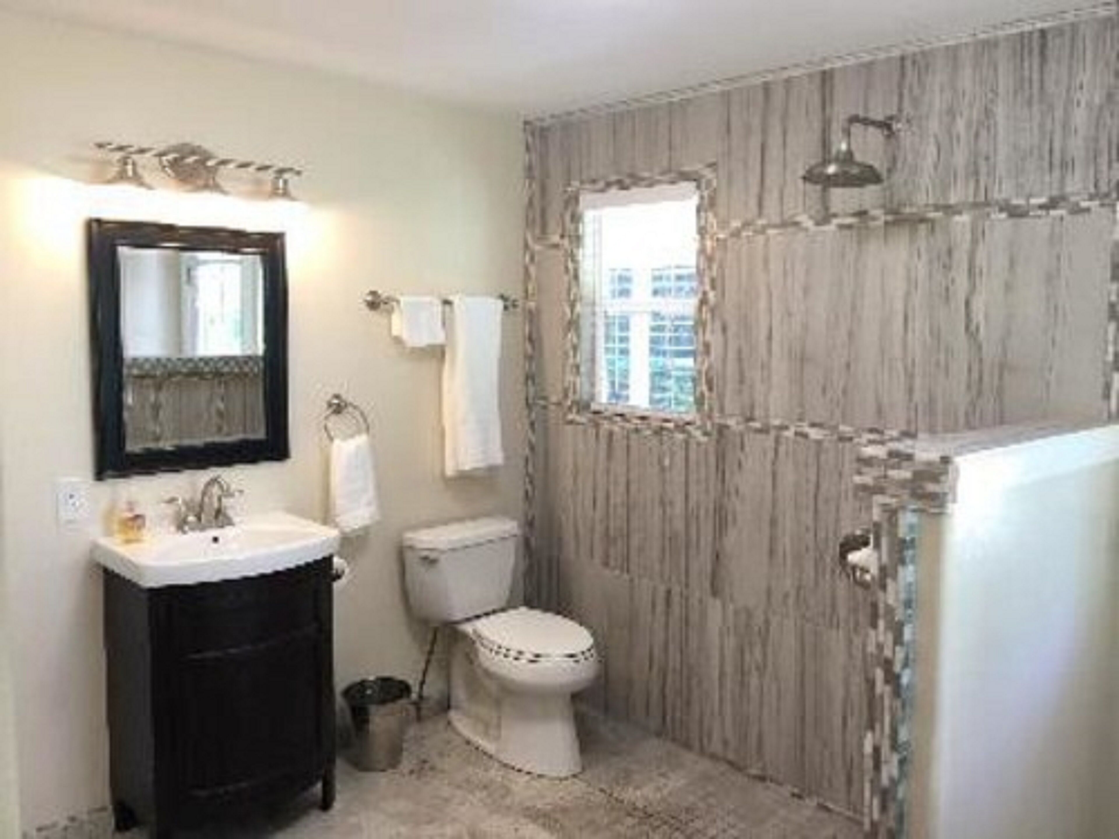 A bathroom with a sink, mirror, toilet, and shower.