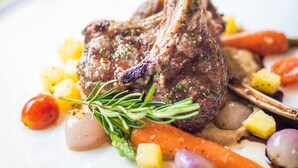 A plate with a lamb chop, vegetables, and a small bowl of sauce. - Horenbecca (Horebeke)