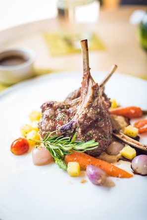 A plate with a lamb chop, vegetables, and a small bowl of sauce. - Horenbecca (Horebeke)
