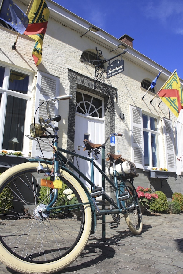 A vintage bicycle with a basket and a bell parked in front of a building with a sign reading "Hotel Restaurant - Bistro". - Horenbecca (Horebeke)