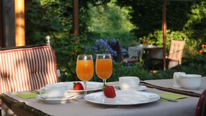 Una mesa lista para el desayuno, con una taza, dos vasos de jugo de naranja, una fresa y un plato de comida.