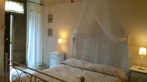 Un dormitorio con una cama, dos mesitas de noche con lámparas, una ventana con cortinas y una puerta.