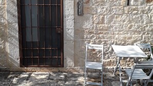 Un edificio de piedra con una puerta de rejas, un letrero pequeño y mesas al aire libre.