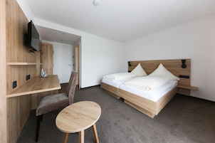 Un dormitorio con una cama de madera, un televisor montado en la pared, un escritorio y una silla.
