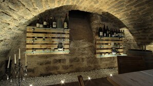 Una celler de vi amb prestatges de fusta que mostren diverses ampolles i recipient de vidre.