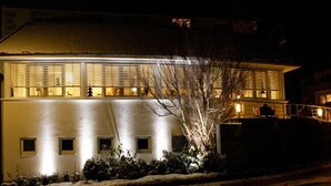 Un edifici modern amb teulada plana i finestres grans, il·luminat durant la nit.