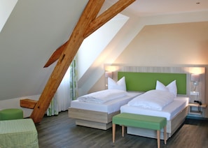 Une chambre moderne avec deux lits, un banc vert et un plafond en pente.