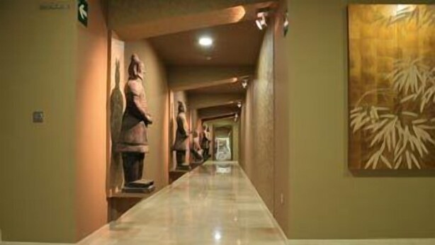 A hallway with marble flooring, statues on the left, and a large wall painting on the right. - Spirit Apartamentos Atxuri (Bilbao)