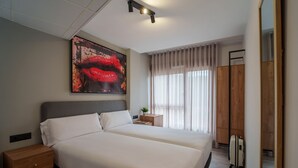 A modern hotel room with a large bed, a nightstand, a small table with a plant, and a large window with curtains. - Spirit Apartamentos Atxuri (Bilbao)