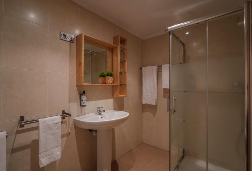 Un baño con lavabo, espejo y cabina de ducha de cristal.