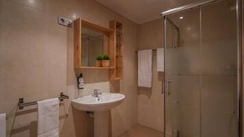 Un baño con lavabo, espejo y cabina de ducha de cristal.