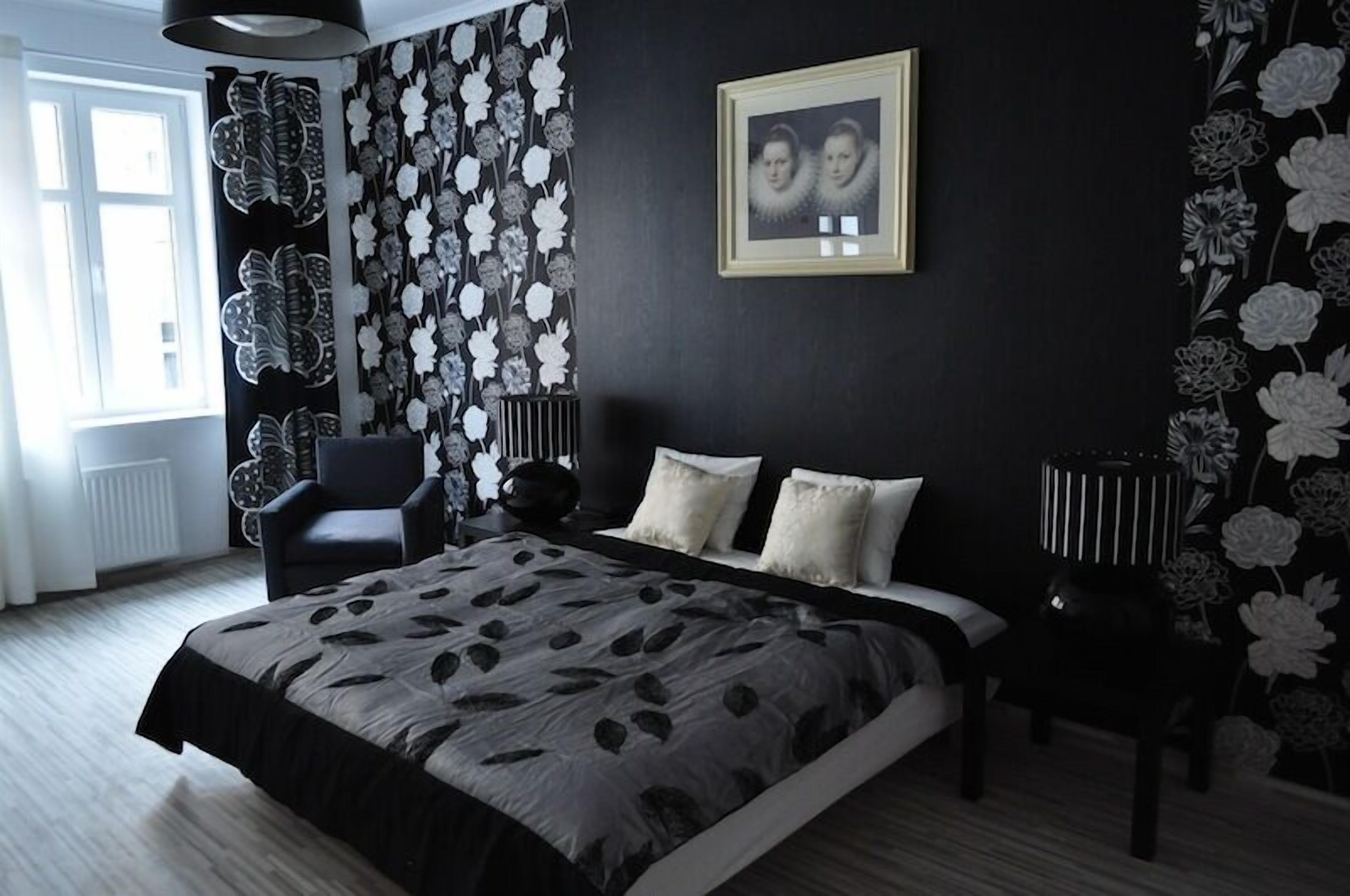 A bedroom with a large bed, a chair, a side table, and a framed photo on the wall.