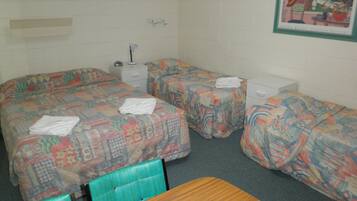 A hotel room with two beds, a small table, and a nightstand.